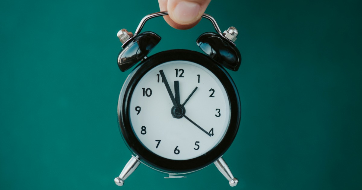 Tiny Alarm Clock Held By Fingers
